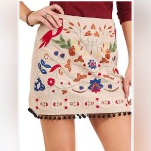 Embroidered skirt with pompom fringe.